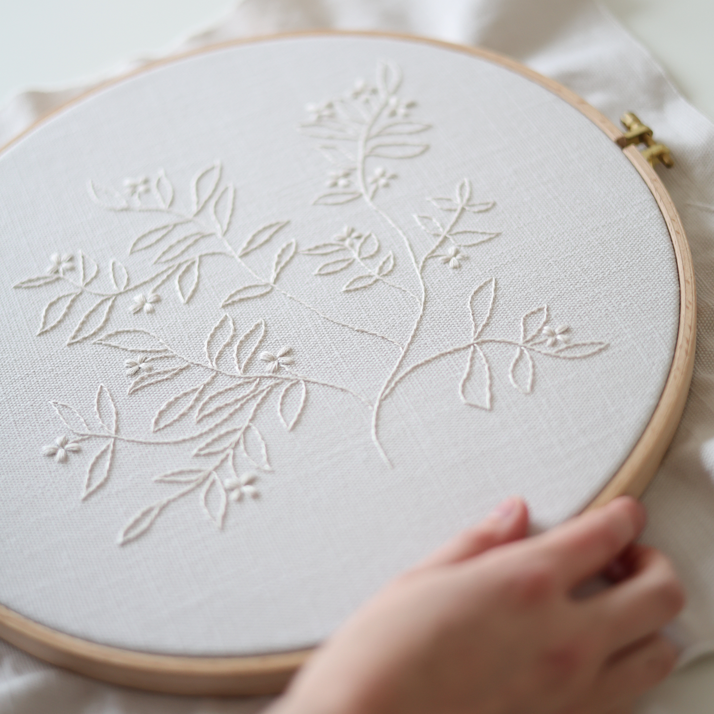 Side view of The Branch embroidery in wooden hoop showing cream thread details