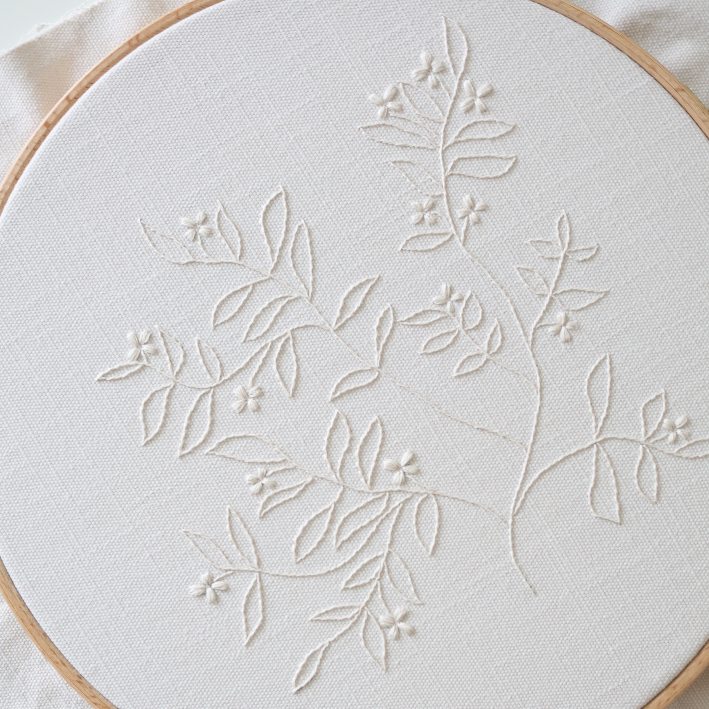 Close-up of The Branch embroidery showing detailed cream thread stitches