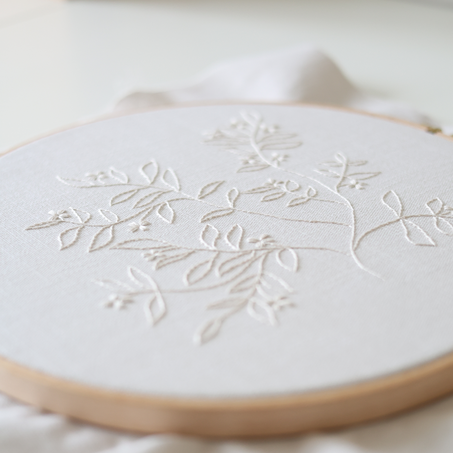Close-up of The Branch embroidery showing detailed cream thread stitches and fabric