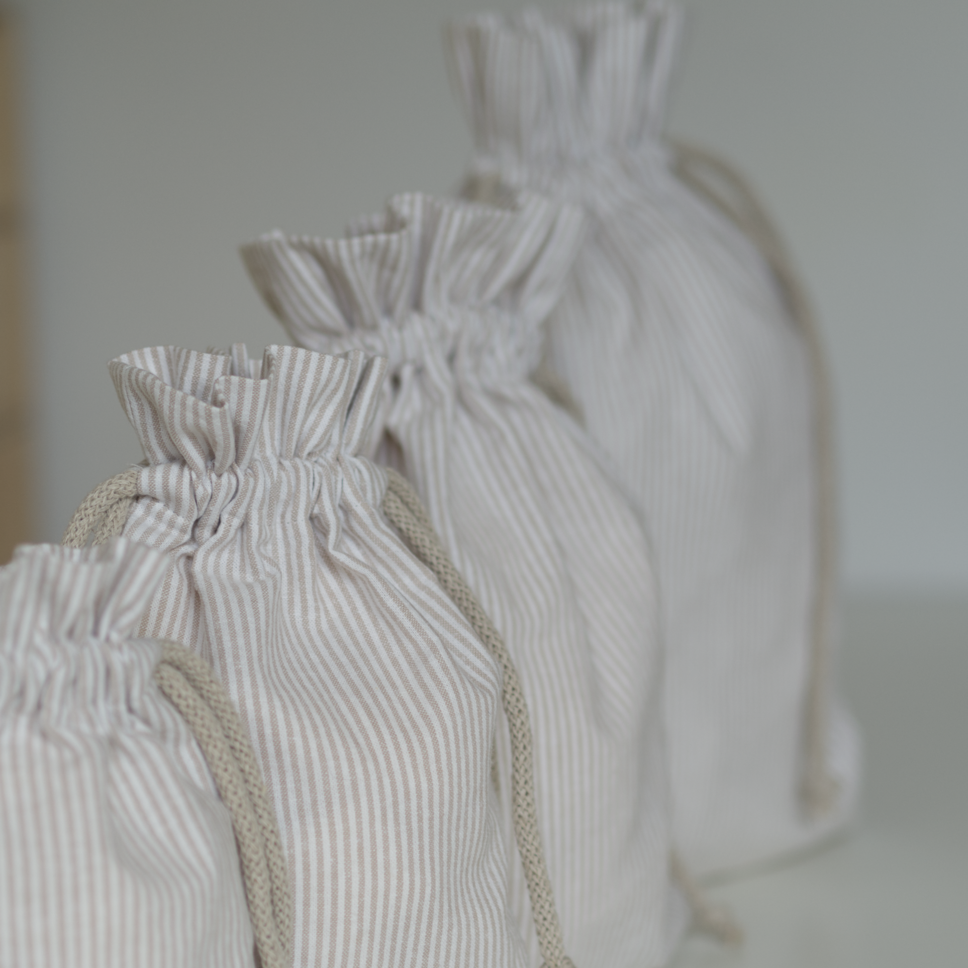 Set of beige striped drawstring bags in various sizes.