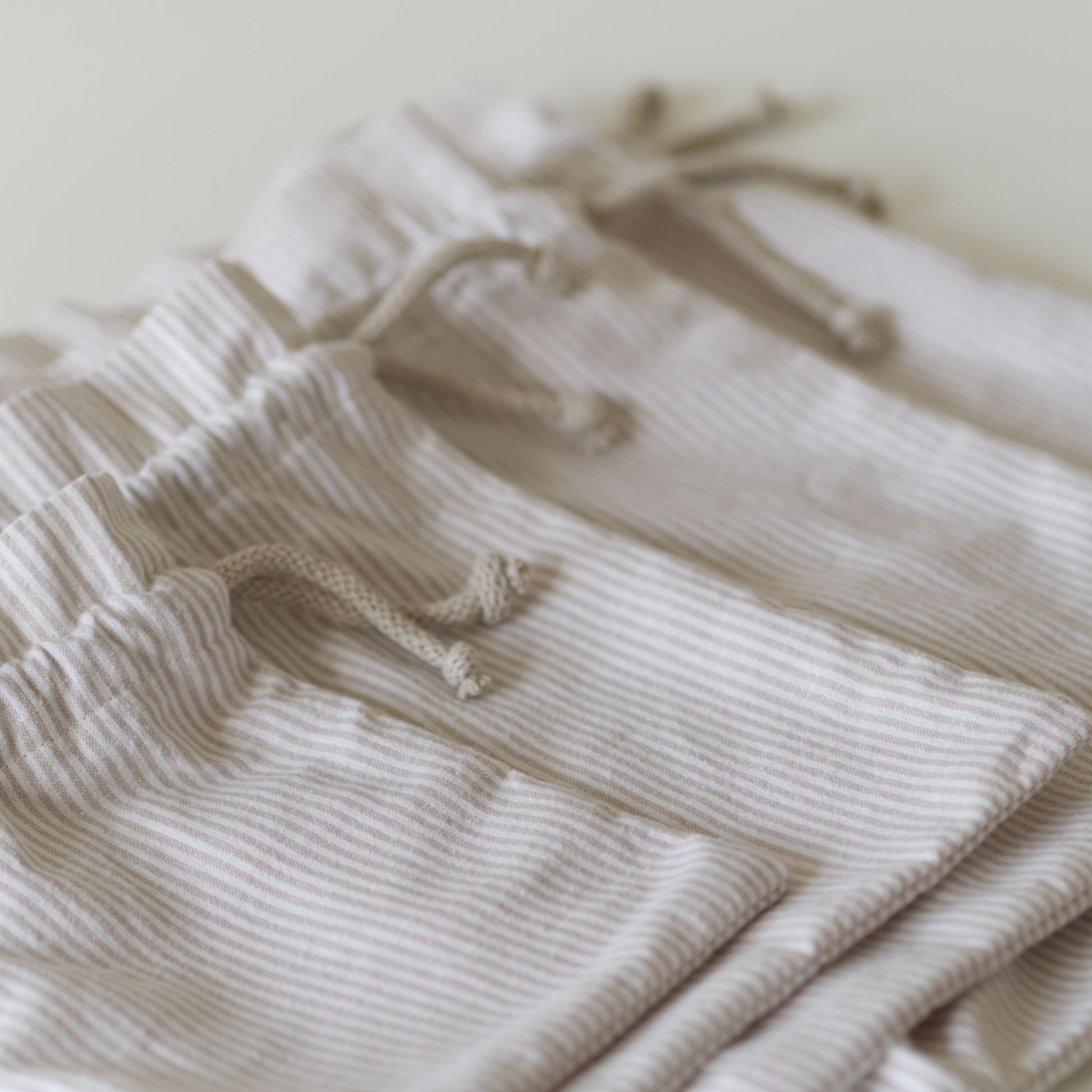 Drawstring bags in striped beige fabric laid flat in multiple sizes for an easy sewing pattern. 