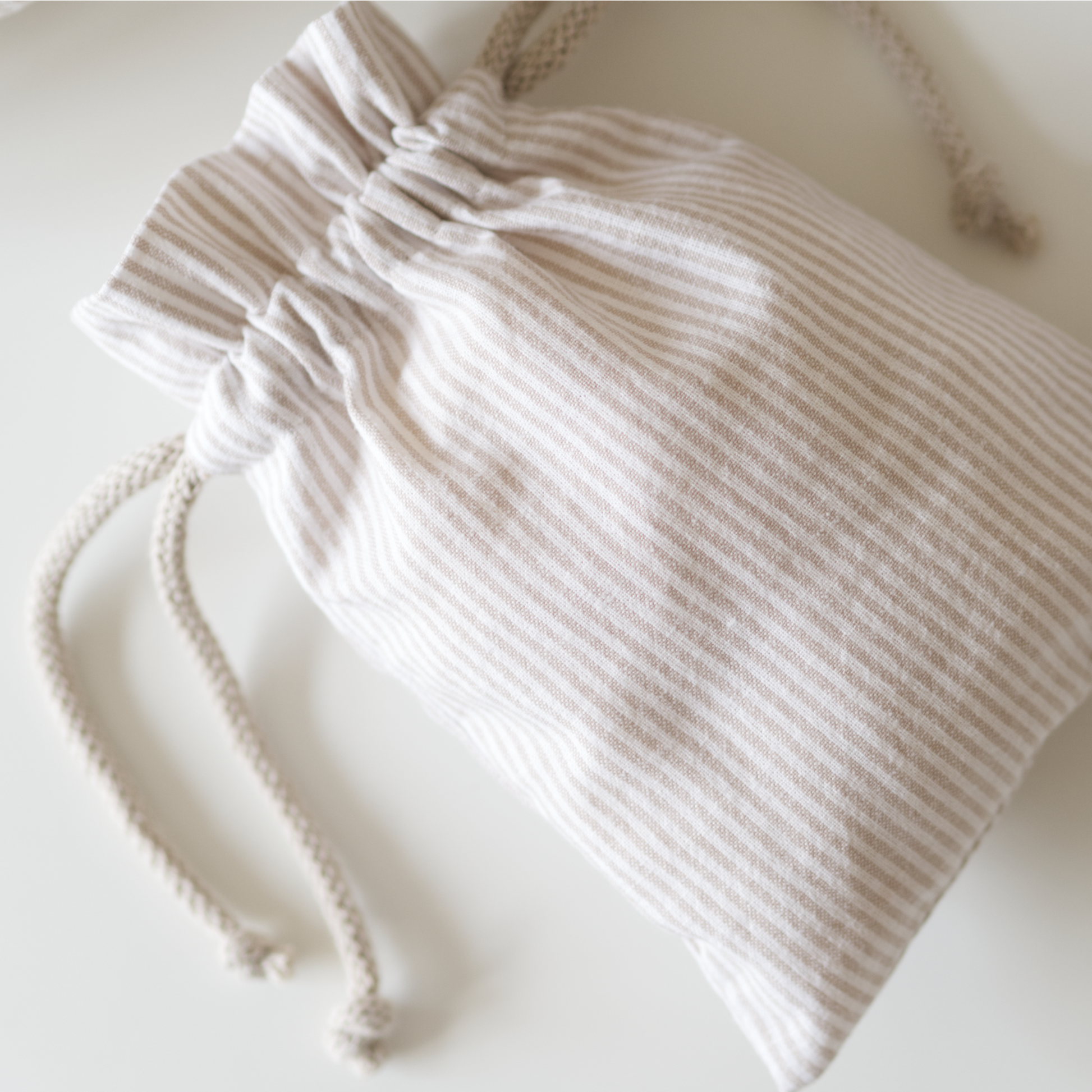 Close up of a small drawstring bag in beige striped fabric.