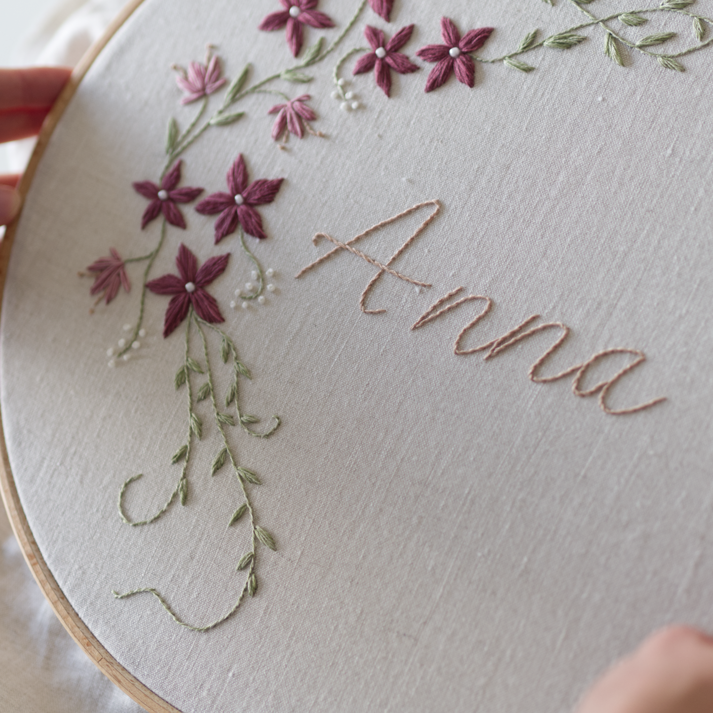 Embroidery hoop with floral design and the name 'Anna' on a light background