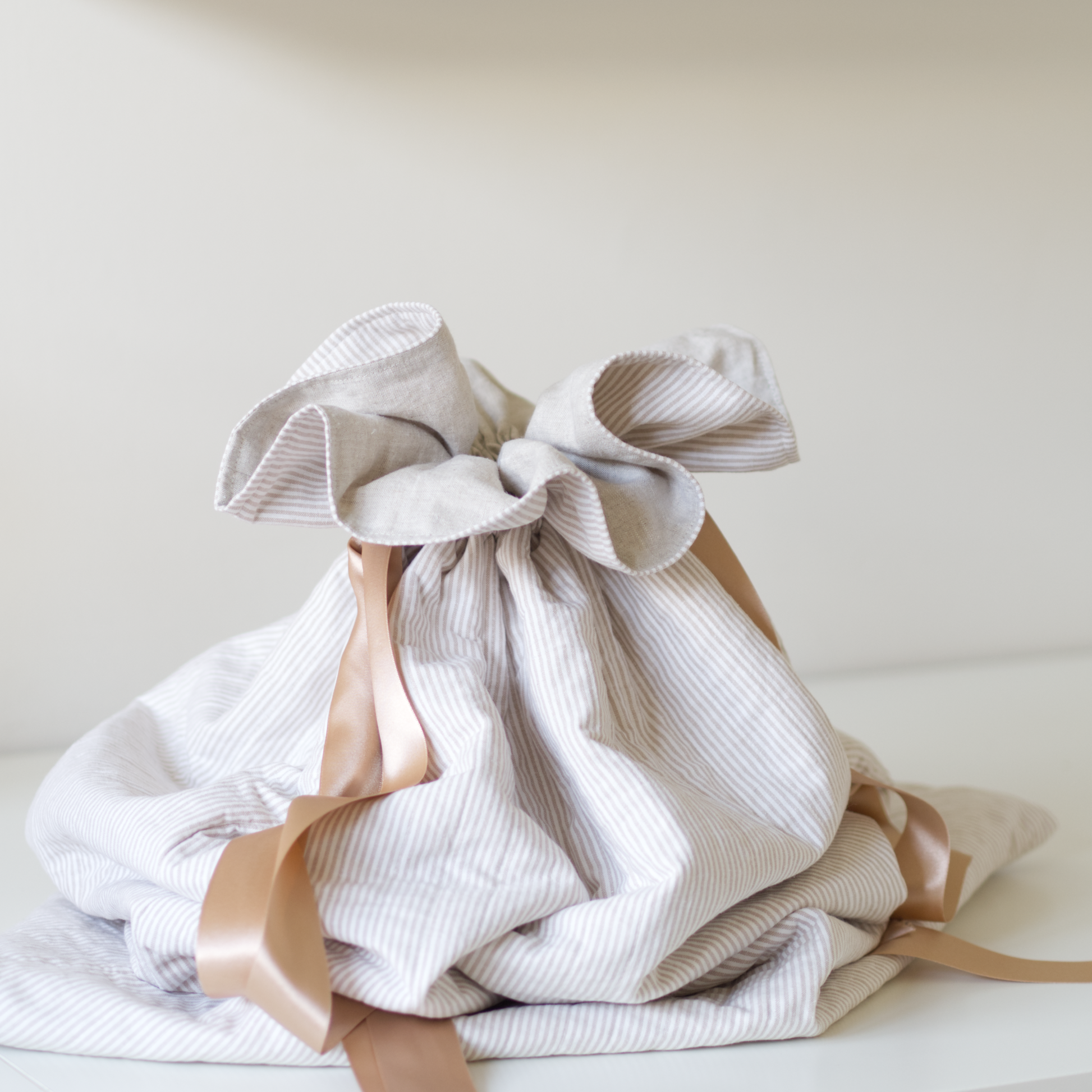 Quilted festive sack in beige striped fabric and gold ribbons.