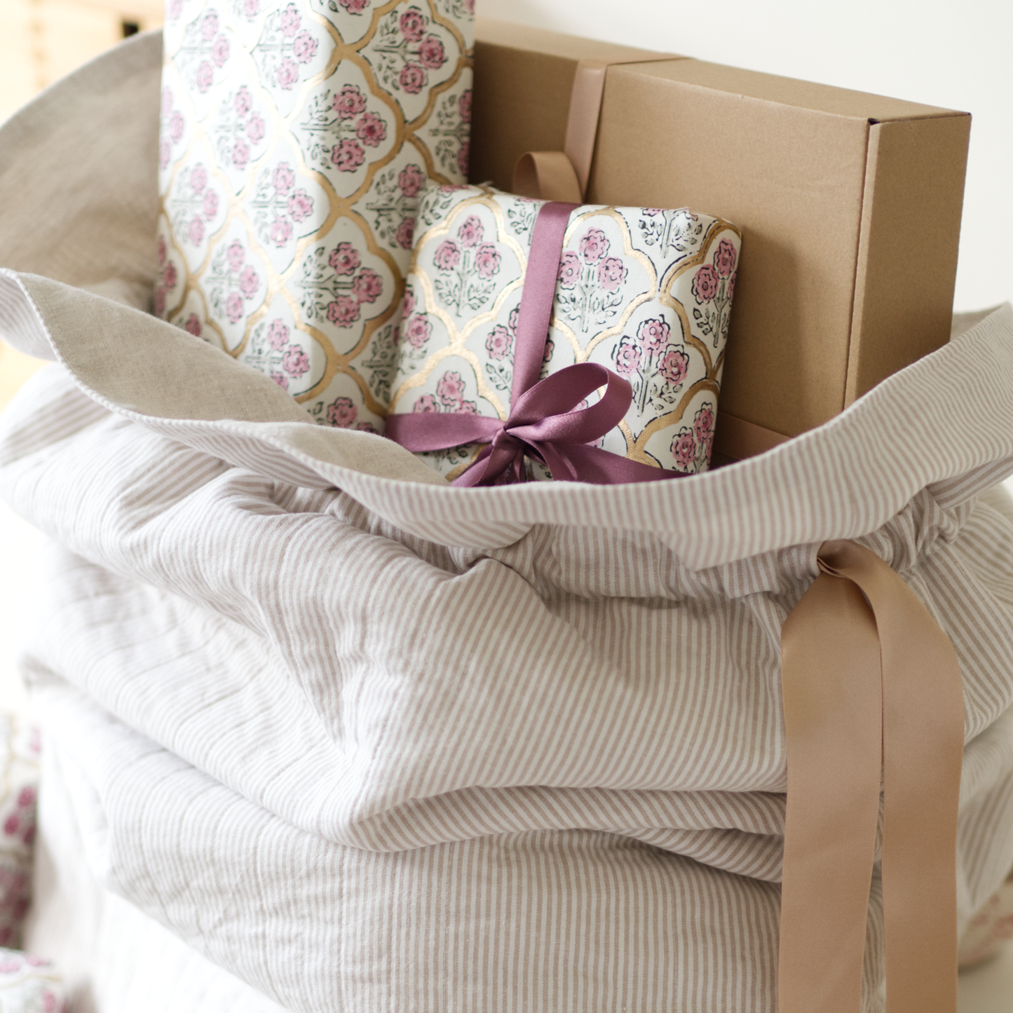 Quilted Santa sack in beige striped fabric and gold ribbons, holding presents tied up in bows.