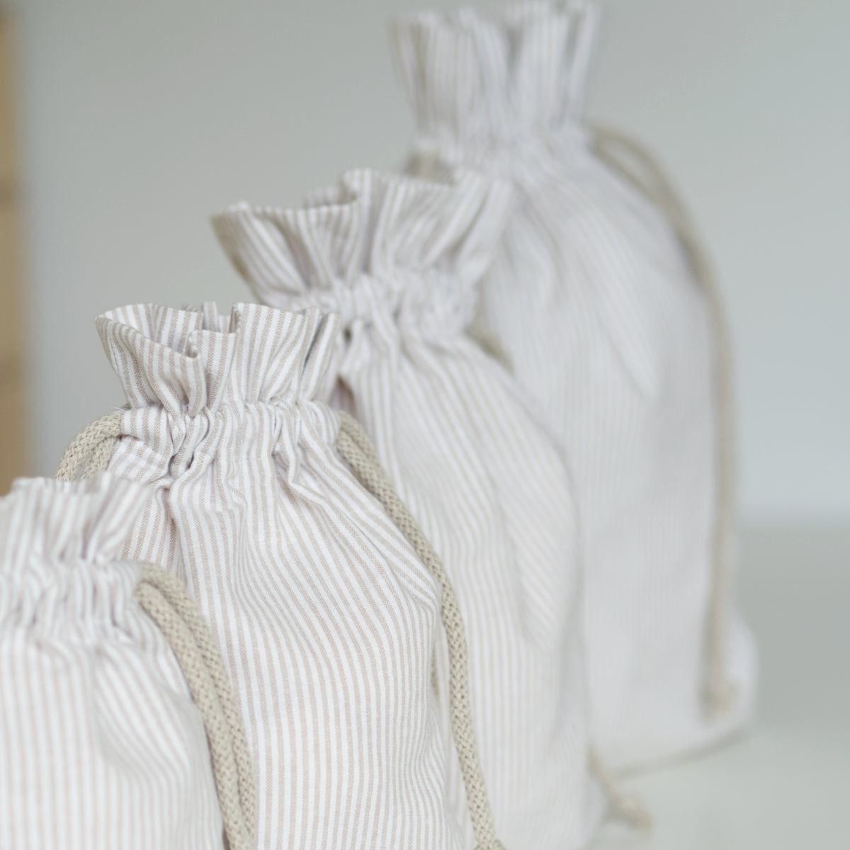 Set of beige striped drawstring bags in various sizes.