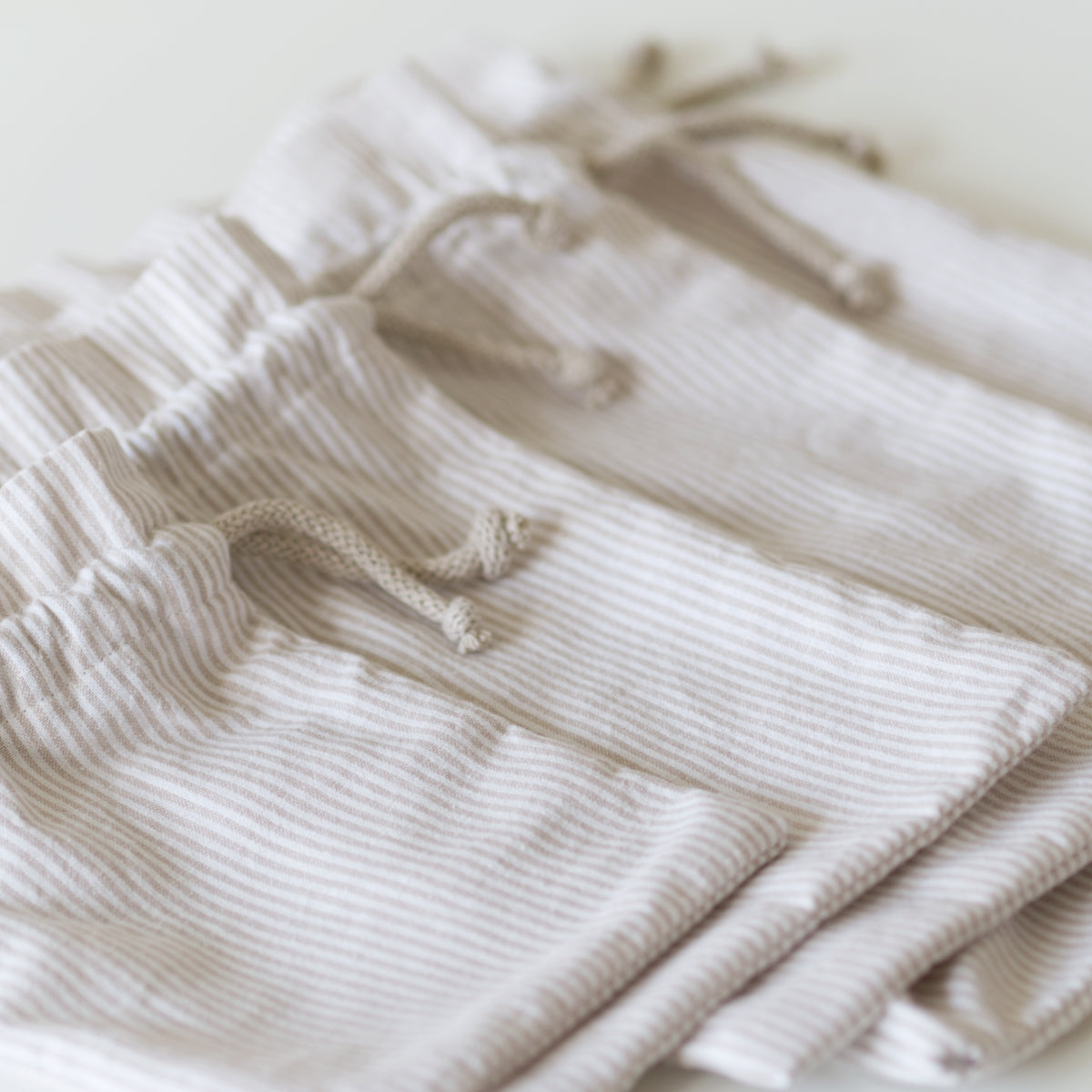 Drawstring bags in striped beige fabric laid flat in multiple sizes for an easy sewing pattern. 